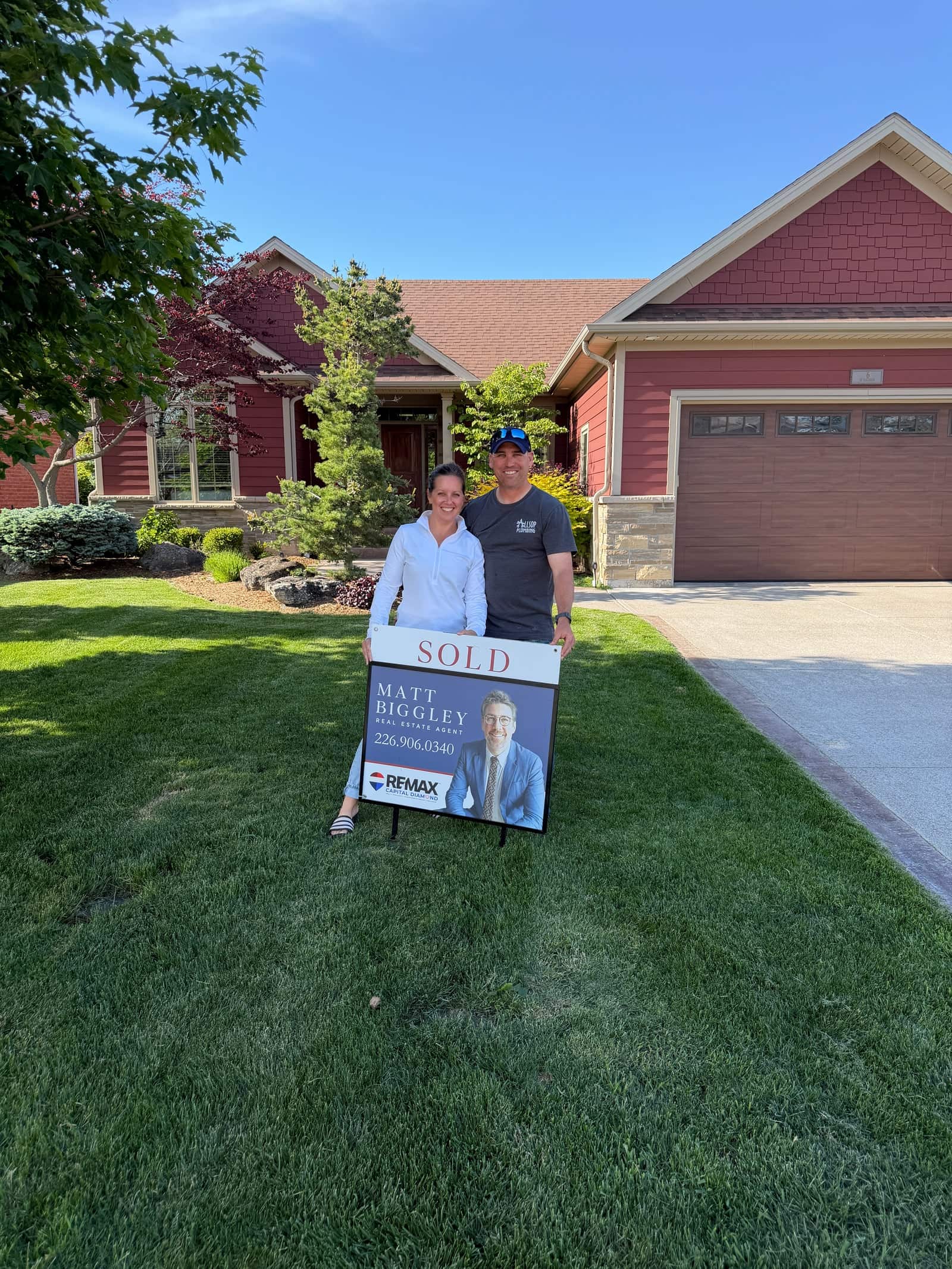 Clients holding a Matt Biggley Sold sign in front of their home