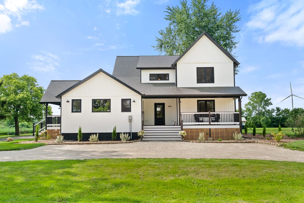 White board and batten farmhouse at 1677 Huffman Road with a covered front porch and gravel circular drive