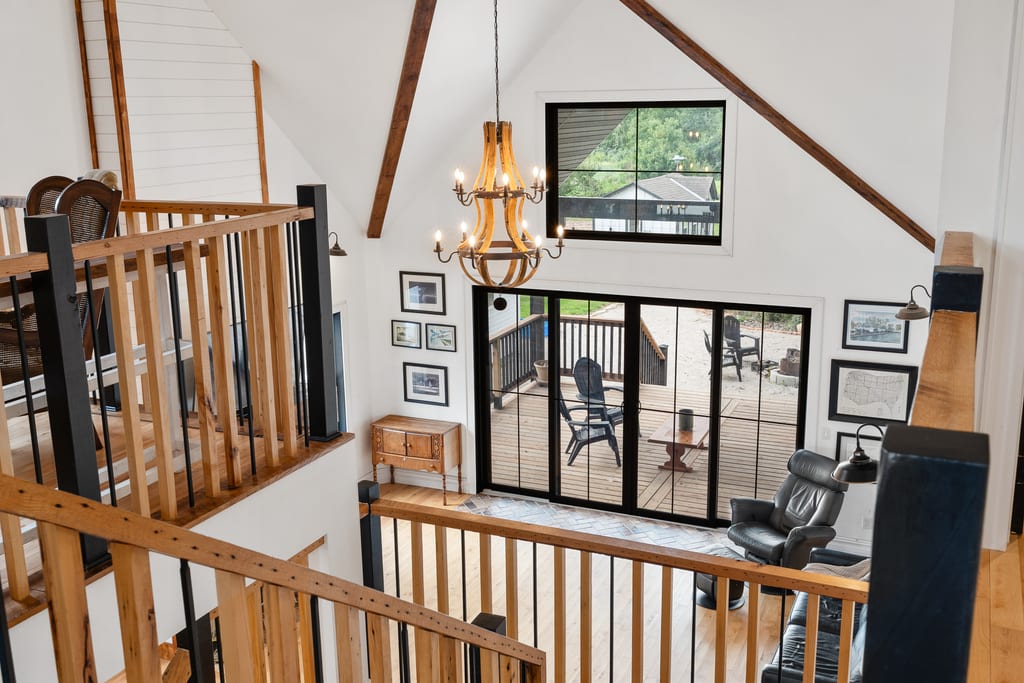View from the upper landing looking down over the great room, with wood railings and exposed beams