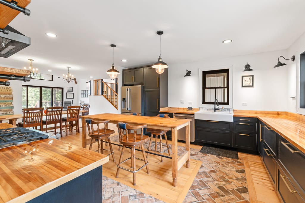 Kitchen with butcher block counters, dark cabinetry, a farmhouse sink, and a brick floor