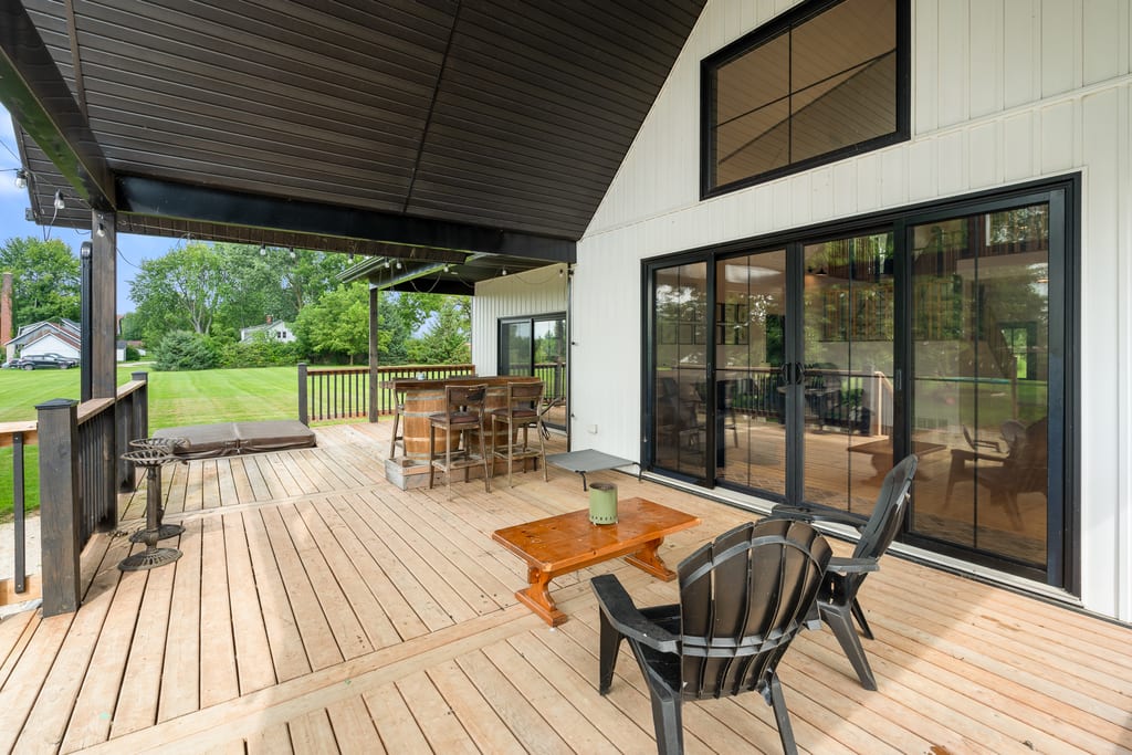Covered rear deck with a vaulted stained ceiling and wide patio doors leading into the great room