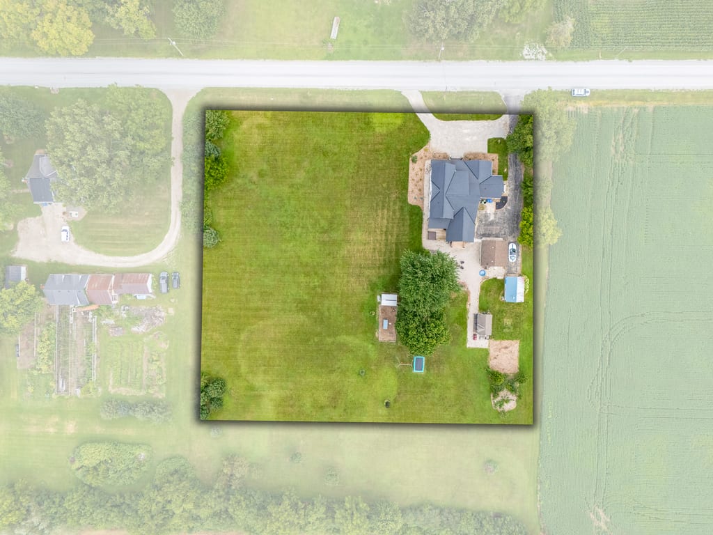 Overhead aerial of the property showing the lot outline, lawn, driveway, and surrounding fields