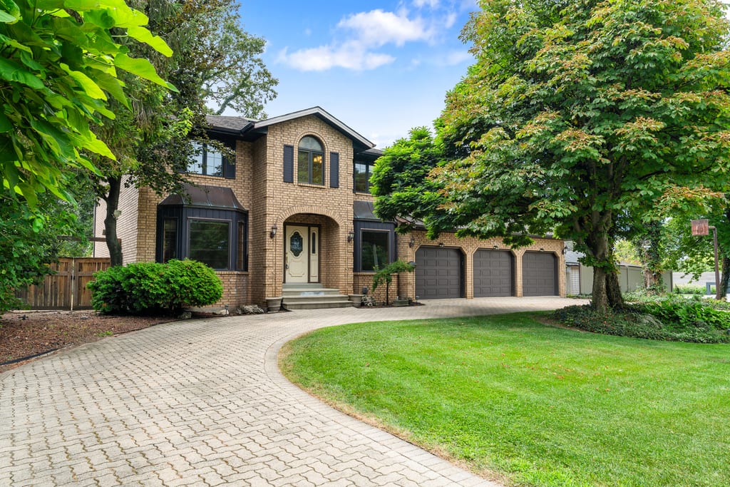 Front elevation of 267 Elmgrove Drive with a brick facade, mature trees, and a sweeping horseshoe driveway