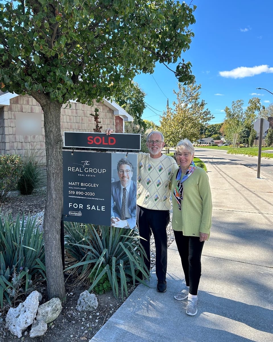 A couple beside a Sold sign outside their home in Windsor-Essex