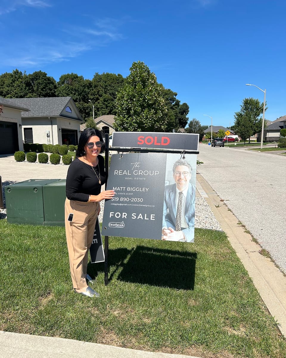 A client beside a Sold sign outside her home in Windsor-Essex