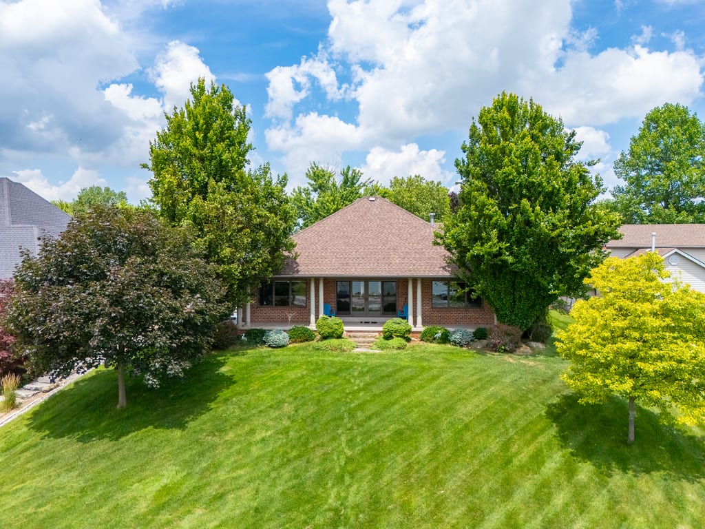 Front elevation of the brick ranch behind a wide lawn framed by mature trees
