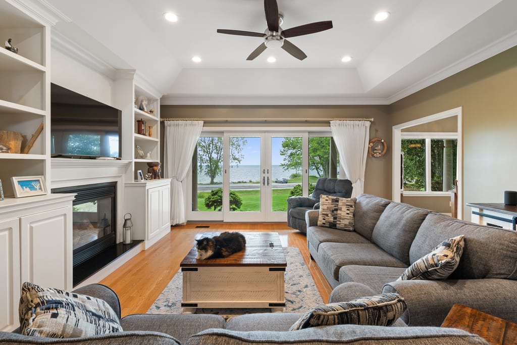 Living room with a gas fireplace, built-in cabinetry, and doors framing the lake view
