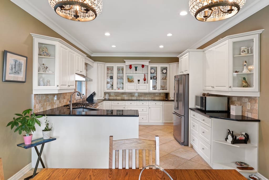 Kitchen with white cabinetry, dark counters, tile floor, and a peninsula
