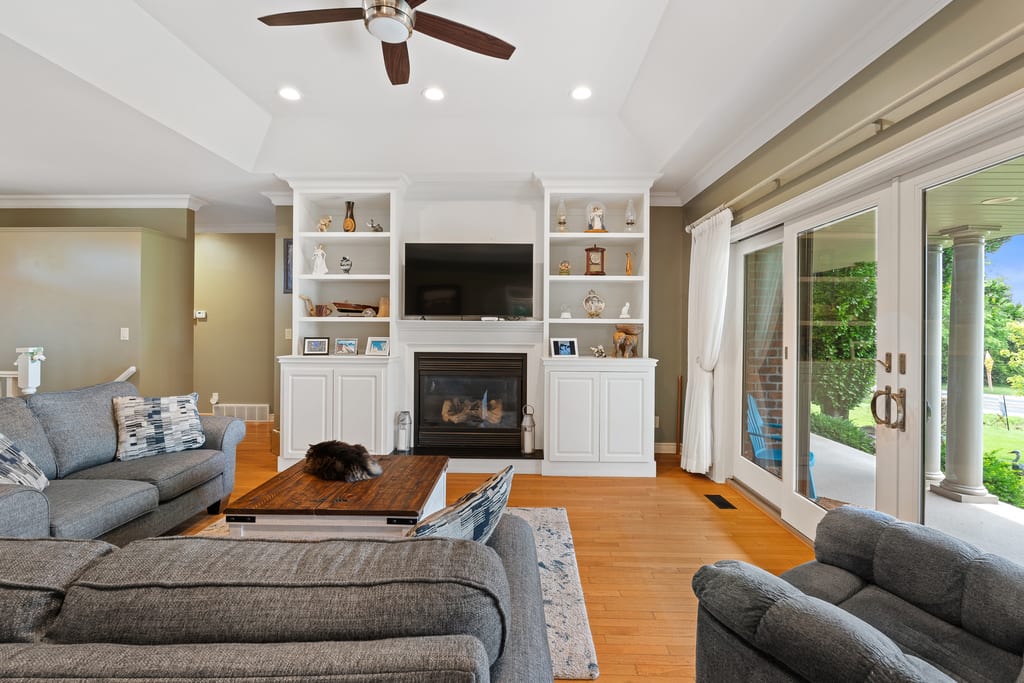 Open great room with hardwood floors, tray ceiling, and doors to the porch