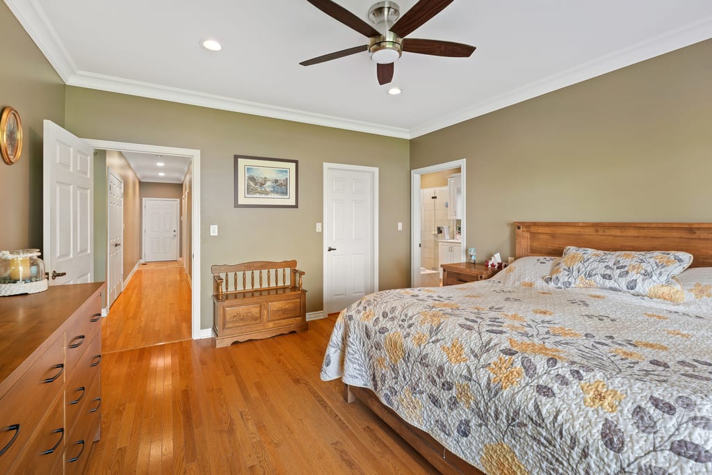 Primary bedroom with hardwood floors and a door through to the ensuite