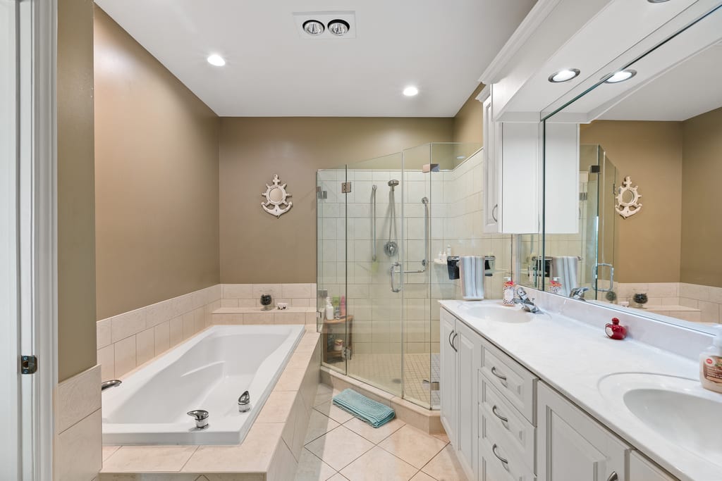 Ensuite bathroom with a soaker tub, glass shower, and double vanity