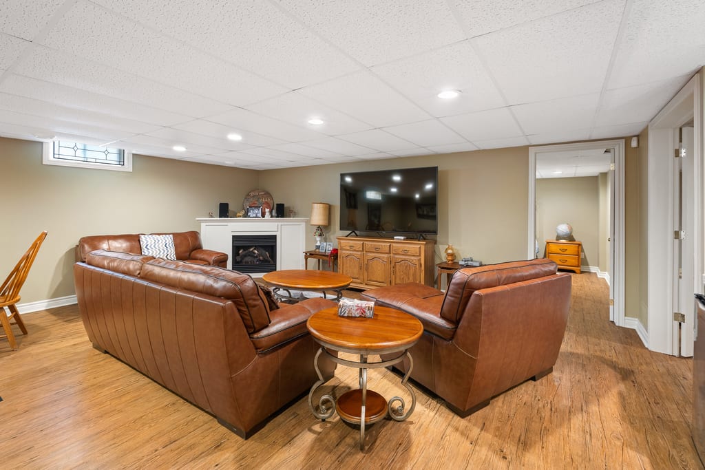 Finished lower level rec room with a pool table, seating area, and fireplace