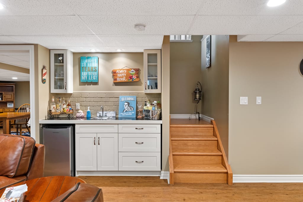 Wet bar in the lower level with cabinetry, counter, and under-counter fridge