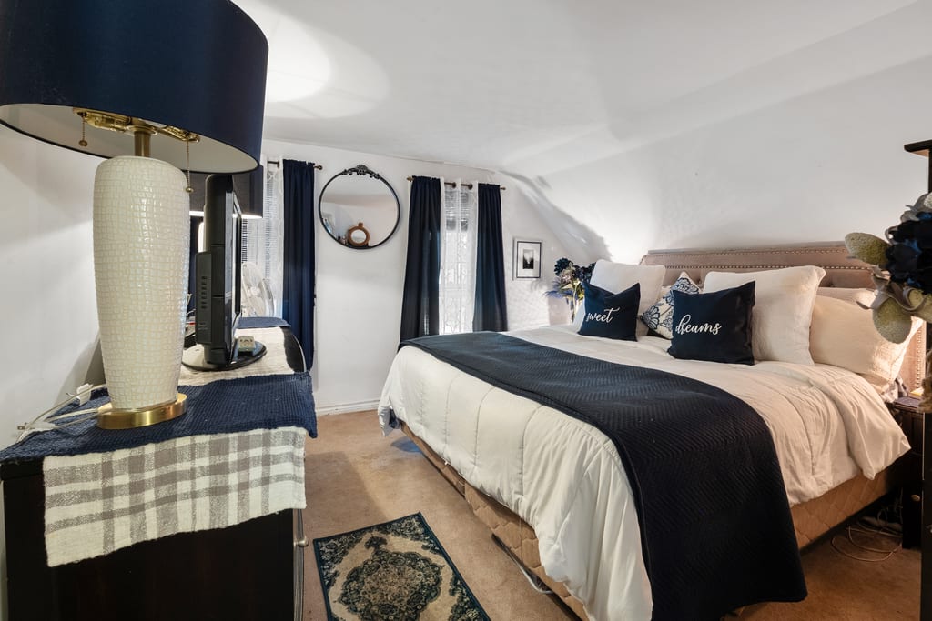 Bedroom with navy bedding, dresser, and a doorway through to the hall