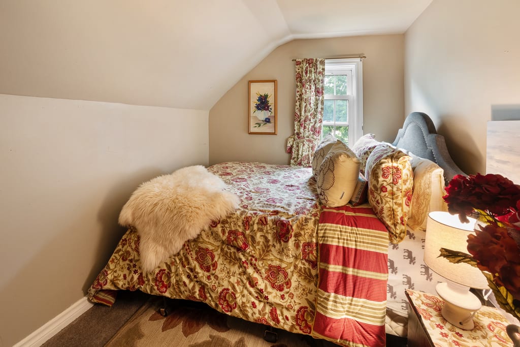 Upper bedroom under a sloped ceiling with a window at the gable end