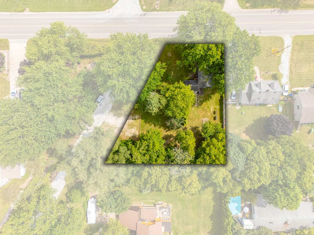 Aerial view showing the property boundary, house, and treed lot from above