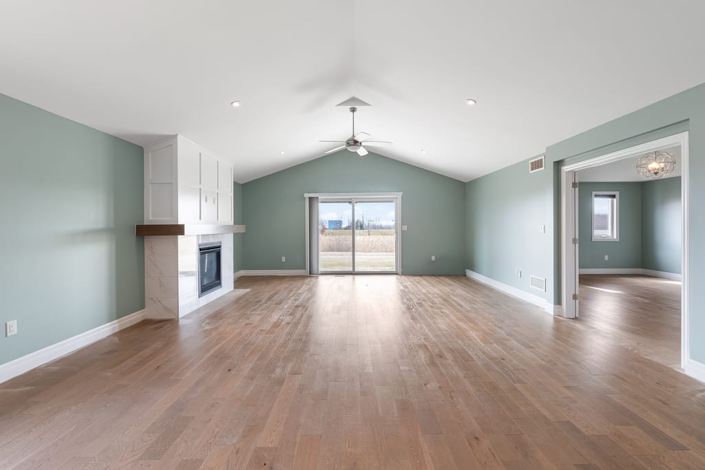 Living room with a cathedral ceiling, hardwood floors, a gas fireplace, and a patio door to the back