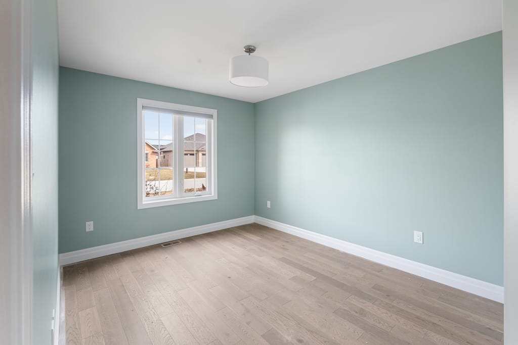 Second bedroom with hardwood floors and a window