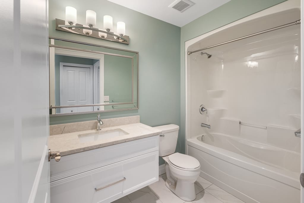 Main bathroom with a white vanity, a framed mirror, and a tub and shower