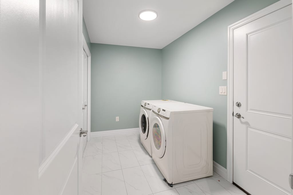 Main-floor laundry room with a front-load washer and dryer and a tile floor