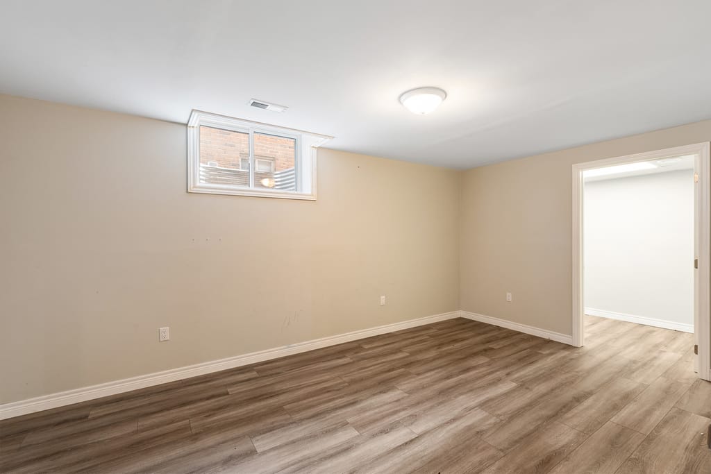 Finished lower-level bedroom with plank flooring and a window