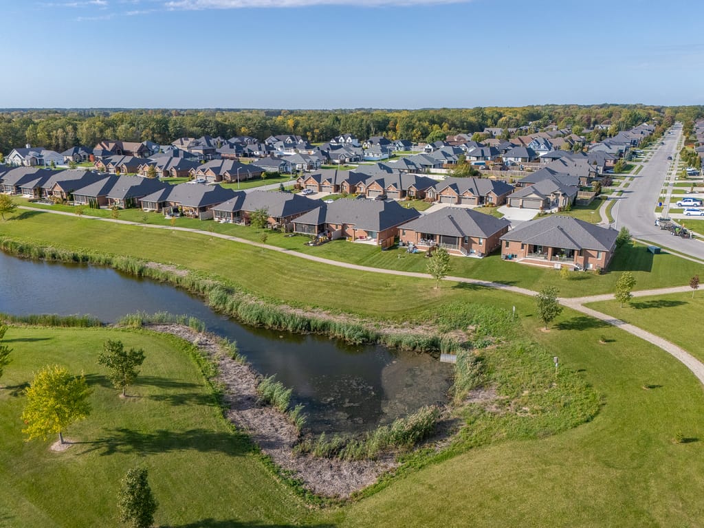 Aerial view of the pond and walking trail behind a row of brick ranch homes