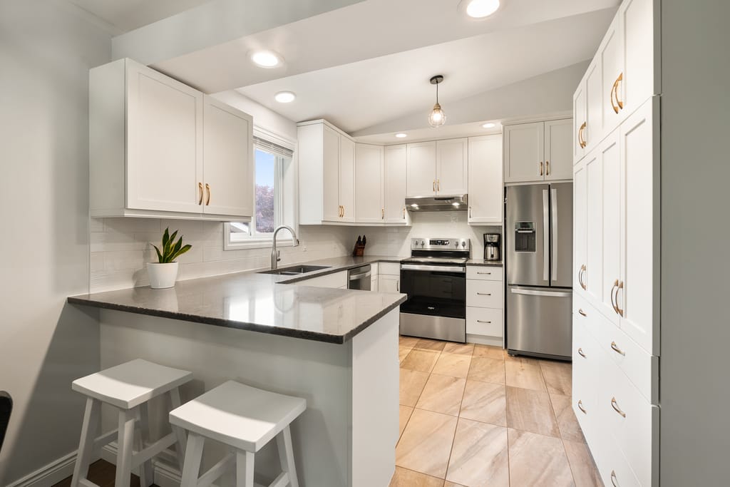 Kitchen with white shaker cabinets, quartz counters, porcelain tile floor, and stainless appliances