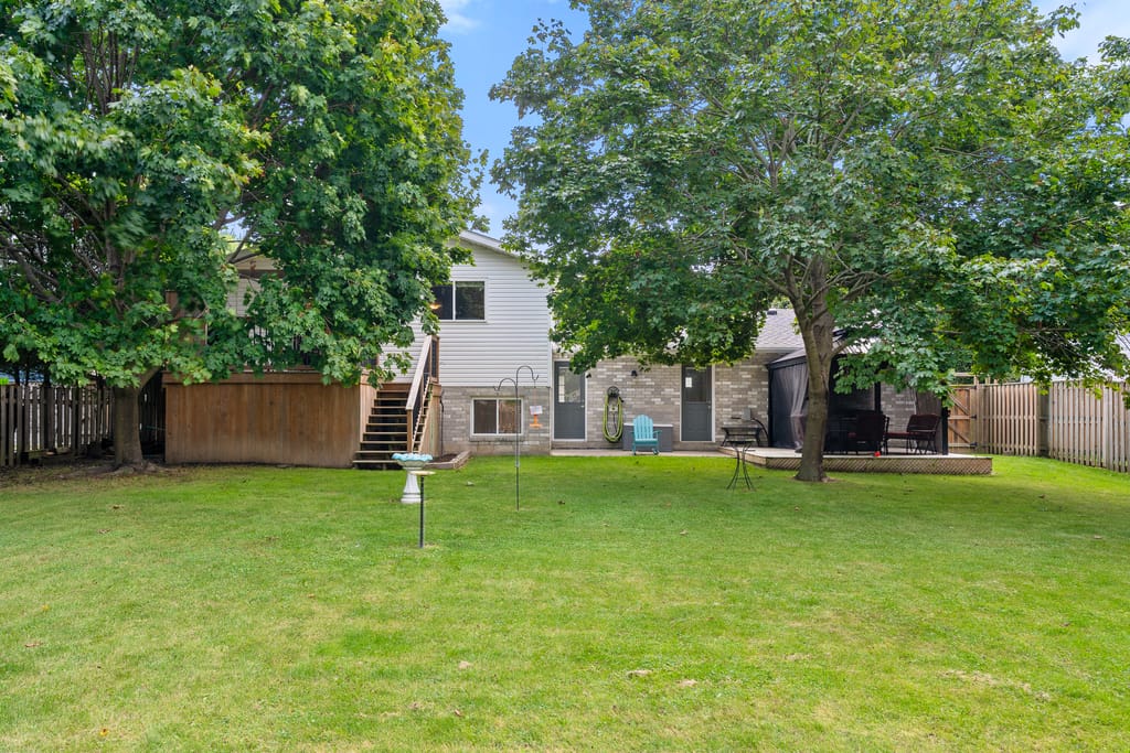 Rear of the house seen from the lawn, with the upper deck, stairs, and gazebo under two mature maples