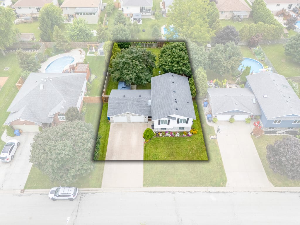 Aerial view with the property outlined, showing the house, the drive, and the treed backyard