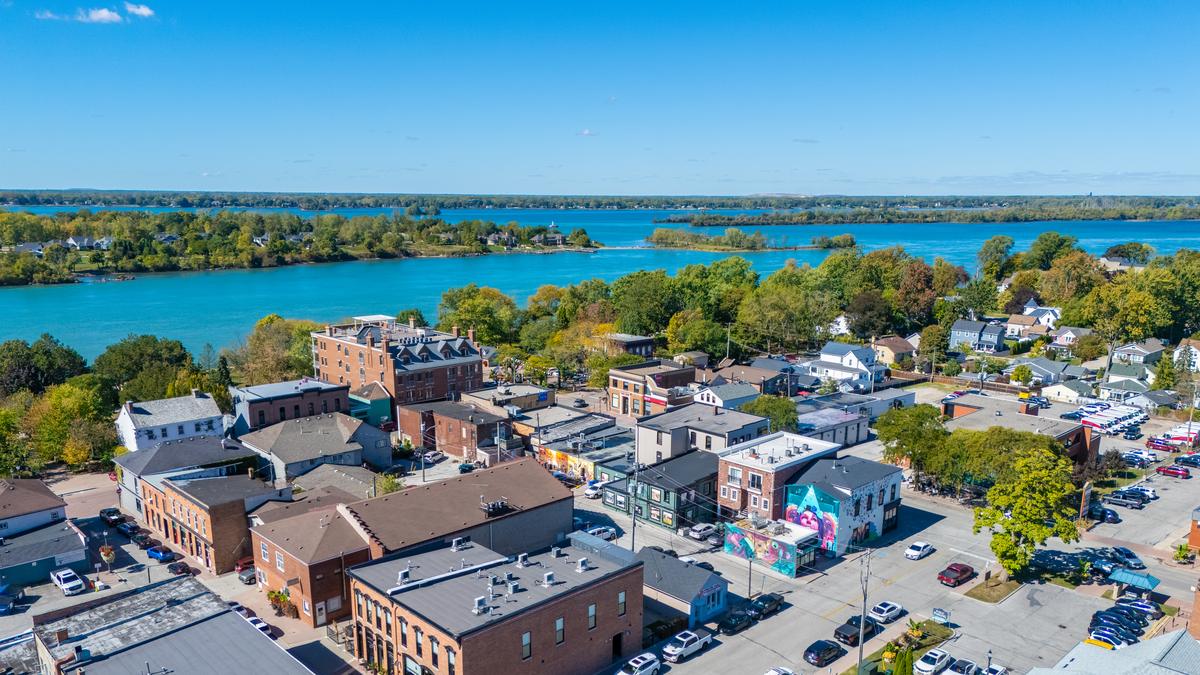 Aerial view over downtown Amherstburg: brick storefronts along Dalhousie Street, residential streets and homes beyond, and Bois Blanc (Boblo) Island across the Detroit River.