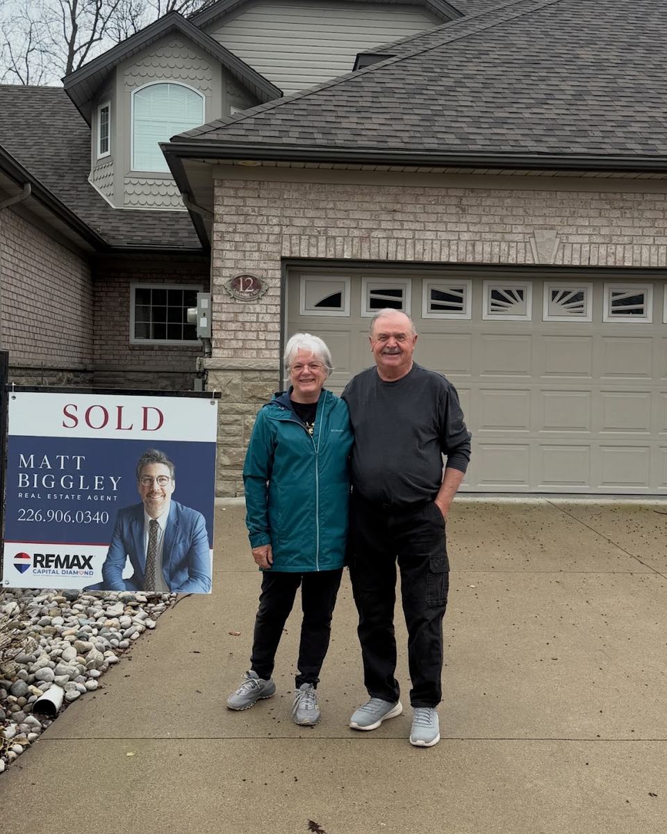 Clients standing beside a Matt Biggley Sold sign in front of the home he sold for them